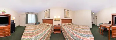 a hotel room with two beds and a tv at Tower Inn and Suites of Guilford / Madison in Guilford