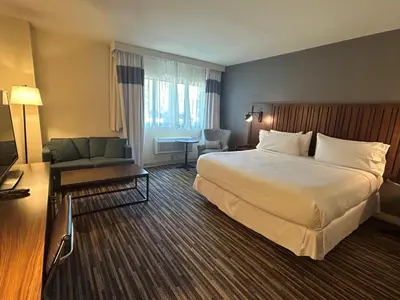 a hotel room with a large bed and a couch at Best Western Premier Plainview-Long Island Hotel in Plainview