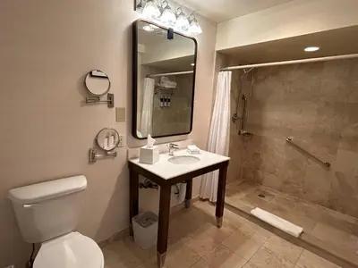 a bathroom with a toilet and a sink and a shower at Best Western Premier Plainview-Long Island Hotel in Plainview