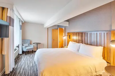 a hotel room with a large bed and a chair at Best Western Premier Plainview-Long Island Hotel in Plainview