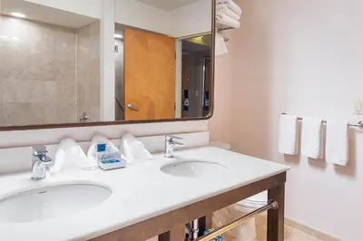 a bathroom with two sinks and a mirror at Best Western Premier Plainview-Long Island Hotel in Plainview