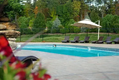 a swimming pool with chairs and an umbrella at The Yankee, Trademark Collection by Wyndham in Lenox
