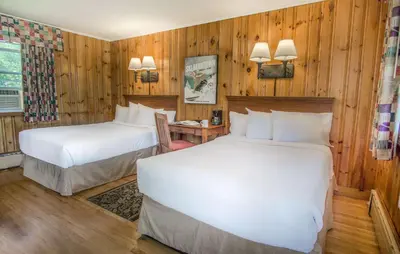 two beds in a room with wooden walls at The Yankee, Trademark Collection by Wyndham in Lenox