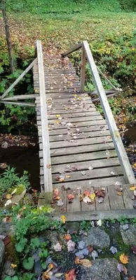 a wooden bridge with a bunch of leaves on it at Whisperin' Pines Chalet in Cooperstown
