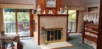 a living room with a fireplace and a balcony at Whisperin' Pines Chalet in Cooperstown