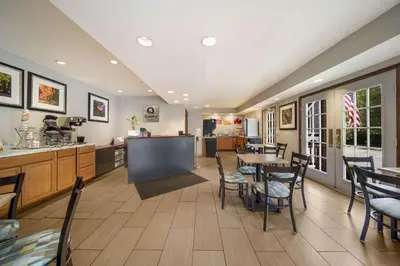 a dining room with tables and chairs and a kitchen at Quality Inn Great Barrington in Great Barrington