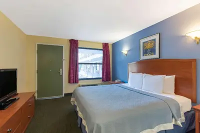 a hotel room with a bed and a television at Days Inn by Wyndham Elmsford in Elmsford