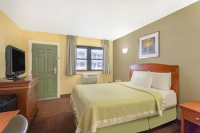 a hotel room with a bed and a flat screen tv at Days Inn by Wyndham Elmsford in Elmsford