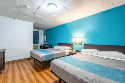 a room with two beds and a blue wall at Motel 6-Elmsford, NY - White Plains in Elmsford