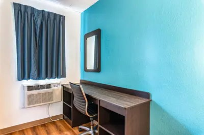 a room with a desk and a blue wall at Motel 6-Elmsford, NY - White Plains in Elmsford