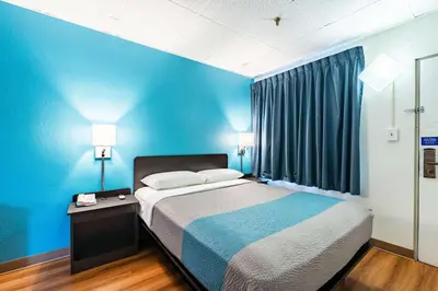 a bed in a room with a blue wall at Motel 6-Elmsford, NY - White Plains in Elmsford