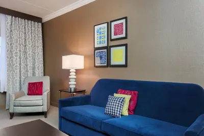 a living room with a blue couch and a chair at Sheraton Tarrytown Hotel in Tarrytown
