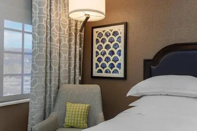 a bedroom with a bed and a chair and a window at Sheraton Tarrytown Hotel in Tarrytown