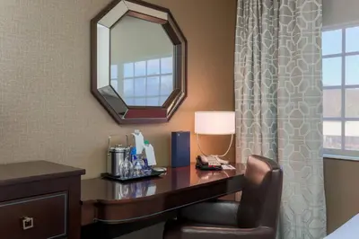 a hotel room with a desk and a mirror at Sheraton Tarrytown Hotel in Tarrytown