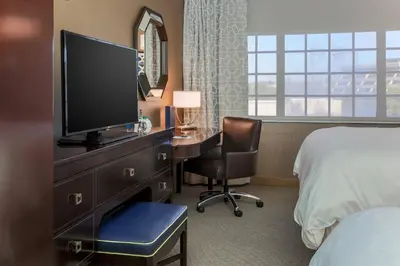 a hotel room with a desk with a television and a bed at Sheraton Tarrytown Hotel in Tarrytown