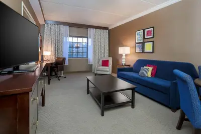 a living room with a blue couch and a tv at Sheraton Tarrytown Hotel in Tarrytown