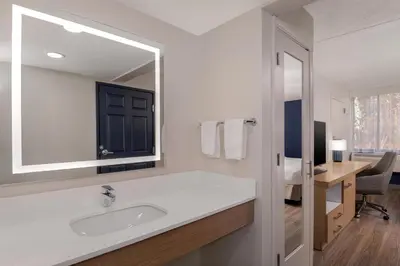 a bathroom with a sink and a mirror and a desk at Spark by Hilton Fishkill in Fishkill
