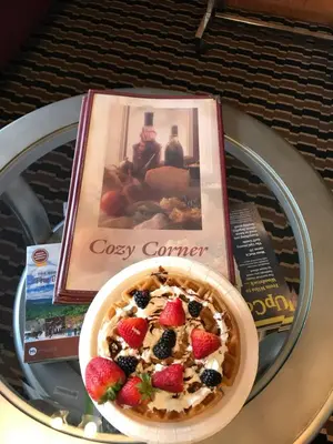 a bowl of cereal with berries on a table with a book at Cozy Corner Motel in Williamstown