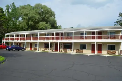 a large white building with red doors and a parking lot at Cozy Corner Motel in Williamstown