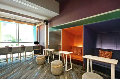 a waiting room with tables and chairs and a window at Tru By Hilton Chicopee Springfield in Chicopee