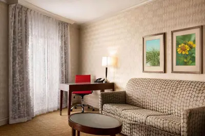 a hotel room with a couch and a desk and a table at Viana Hotel and Spa, Trademark Collection by Wyndham in Westbury