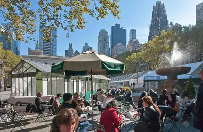 a group of people sitting at tables in front of a fountain at Modern Midtown East Apartments in NYC in New York