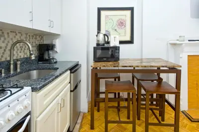 a kitchen with a sink and a counter with stools at Modern Midtown East Apartments in NYC in New York