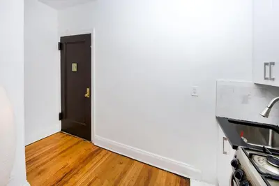 a kitchen with a black door and a wooden floor at Modern Midtown East Apartments in NYC in New York