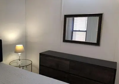 a bedroom with a dresser and a mirror on the wall at Modern Midtown East Apartments in NYC in New York