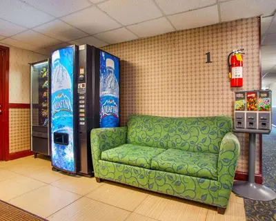 a room with a green couch and a soda machine at Rodeway Inn Meadowlands in Secaucus