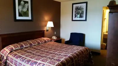 a hotel room with a bed and a blue chair at Travel Inn Motel in Hartford