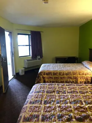 a hotel room with two beds and a window at Travel Inn Motel in Hartford