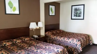 a hotel room with two beds and two lamps at Travel Inn Motel in Hartford
