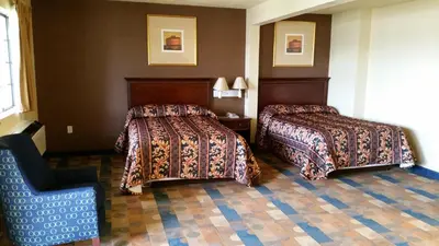 a hotel room with two beds and a chair at Travel Inn Motel in Hartford