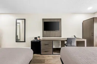 a hotel room with two beds and a desk with a television at Quality Inn in West Haven