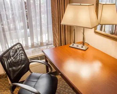 a hotel room with a desk with a lamp and a chair at Comfort Inn Wethersfield - Hartford in Wethersfield