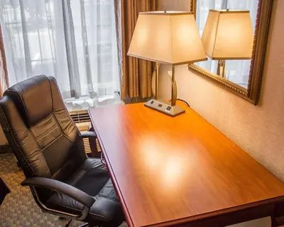 a desk in a hotel room with a chair and a lamp at Comfort Inn Wethersfield - Hartford in Wethersfield