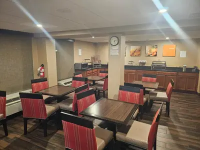 a restaurant with tables and chairs and a clock on the wall at Comfort Inn Wethersfield - Hartford in Wethersfield