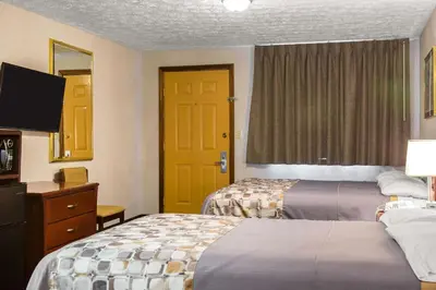 a hotel room with two beds and a yellow door at Rodeway Inn & Suites Branford - Guilford in Branford