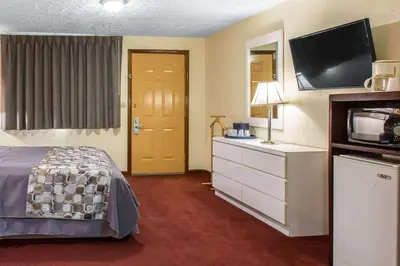 a hotel room with a bed and a tv at Rodeway Inn & Suites Branford - Guilford in Branford