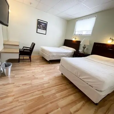 a bedroom with two beds and a desk and a chair at Baseball Town Motel in Cooperstown