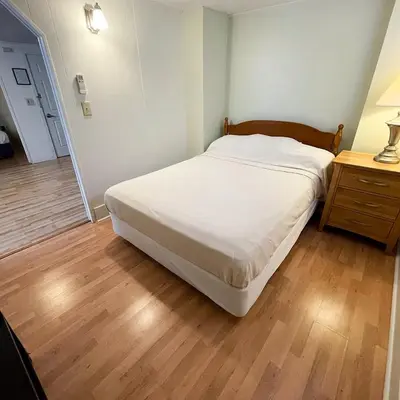 a bedroom with a white bed and a wooden floor at Baseball Town Motel in Cooperstown