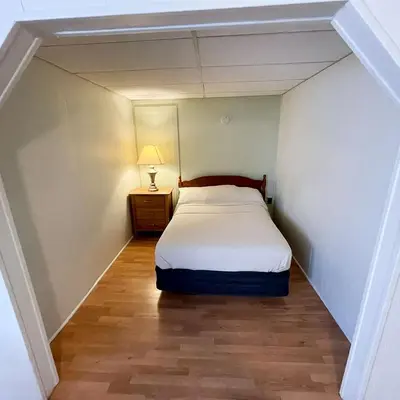 a small bedroom with a bed and a lamp in it at Baseball Town Motel in Cooperstown