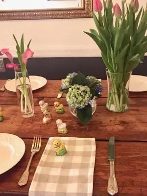a wooden table topped with plates and vases with flowers at The Nutmeg Vermont in Wilmington