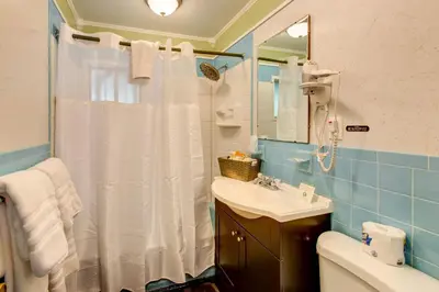 a bathroom with a white shower curtain and a sink at Starlite Motel & Suites in Big Indian