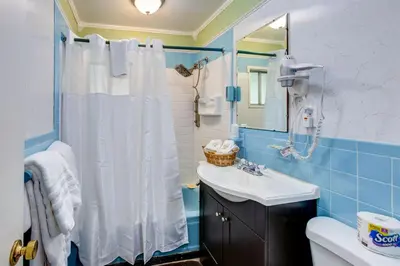 a bathroom with a white shower curtain and a sink at Starlite Motel & Suites in Big Indian