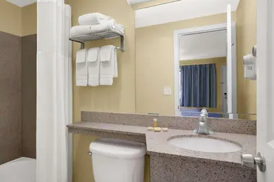 a bathroom with a sink and a toilet and a mirror at Days Inn by Wyndham Middletown in New Hampton