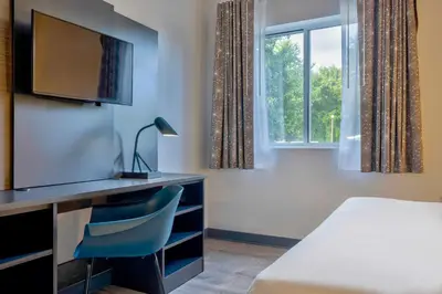 a room with a bed and a desk with a television at Motel 6 Bethel, CT - Danbury in Bethel