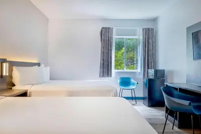 a hotel room with two beds and a desk and a window at Motel 6 Bethel, CT - Danbury in Bethel