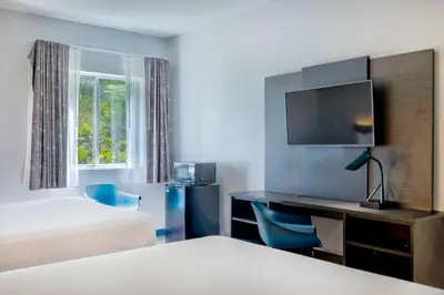 a hotel room with a bed and a desk with a tv at Motel 6 Bethel, CT - Danbury in Bethel